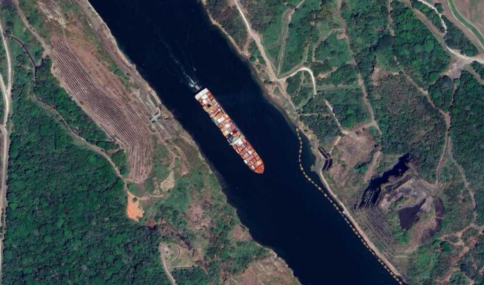Aerial view of a cargo ship navigating a river surrounded by greenery