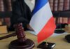 A gavel and a small French flag on a desk in a courtroom setting