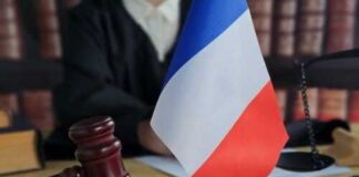 A gavel and a small French flag on a desk in a courtroom setting