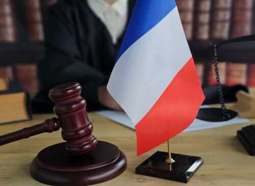 A gavel and a small French flag on a desk in a courtroom setting