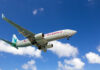 An airplane flying through a clear blue sky with clouds
