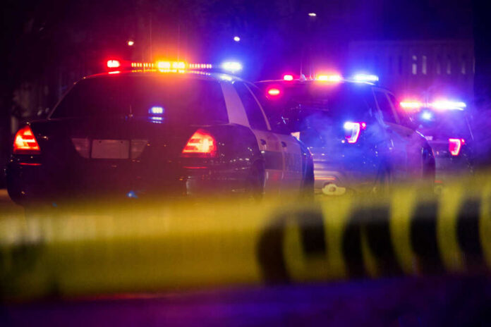 shutterstock1349511497jpg Police cars with flashing lights at a nighttime scene behind crime scene tape