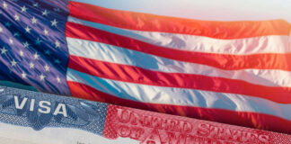 Close-up of a US visa with an American flag in the background