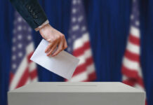 Missing Records Fuel Million-Dollar Questions A hand placing a ballot into a ballot box with American flags in the background