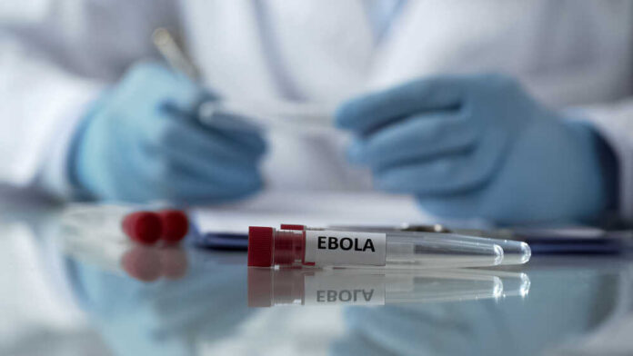 Ebola test tube on lab table with gloved researcher in background