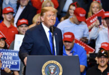 Mental-Health Claims on Trump: A Political Weapon? A speaker at a political rally smiling in front of an enthusiastic crowd wearing red hats