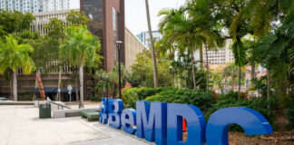 Large blue sculpture in an urban park with palm trees