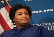 A political figure speaking at a podium with a blue backdrop