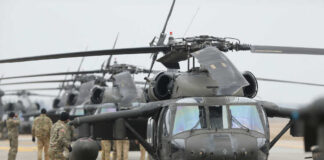 Military personnel preparing helicopters on an airbase