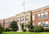Exterior view of a brick school building with an American flag