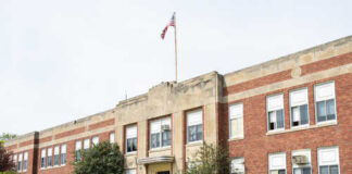 Exterior view of a brick school building with an American flag
