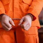 Safeguards Shattered: Predator Trolled UK Classrooms A person in an orange jumpsuit with handcuffs