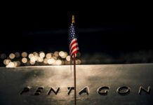Pentagon’s Billion-Dollar AI Gamble: Truth or Hype? A small American flag positioned in front of the word 'PENTAGON' on a reflective surface