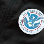 Trump-Era Playbook Returns—Bar Fumes Close-up of a U.S. Department of Homeland Security badge on a black jacket