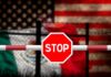 Disturbing Discovery at US-Mexico Border! Stop sign on barrier with blurred U.S. and Mexico flags behind fence