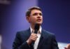 Culture War Grenade Rocks Texas Senate A man in a suit speaking into a microphone at a conference