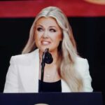 A female speaker presenting at a conference with a microphone