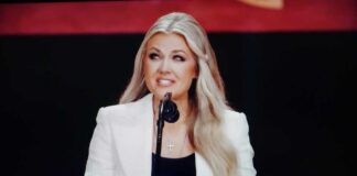A female speaker presenting at a conference with a microphone