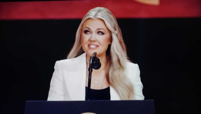 A female speaker presenting at a conference with a microphone