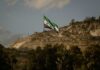 Syrian flag waving in front of a mountainous landscape