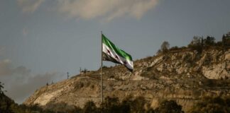 Syrian flag waving in front of a mountainous landscape