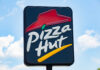 restaurant sign with red roof logo against blue sky