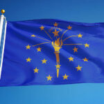Indiana state flag waving against a blue sky