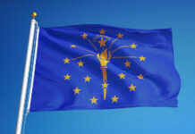 Indiana state flag waving against a blue sky