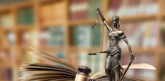 A gavel and a statue of Lady Justice beside an open law book