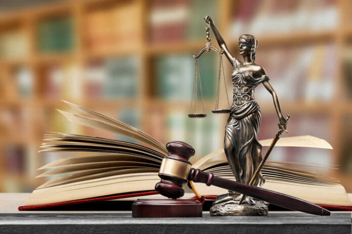 Open,Law,Book,In,Library A gavel and a statue of Lady Justice beside an open law book