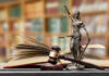 A gavel and a statue of Lady Justice beside an open law book