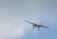 Small propeller airplane flying against a cloudy sky