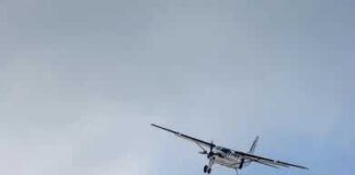 Small propeller airplane flying against a cloudy sky
