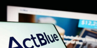 Close-up of ActBlue logo on a mobile device with a website in the background