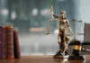 How A Base Dispute Turned Deadly A bronze statue of Lady Justice holding scales and a sword, with law books and a gavel in the foreground