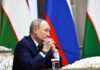 A government official sitting at a conference table with a serious expression