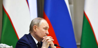 A government official sitting at a conference table with a serious expression