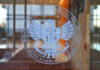 Insider Tapped To Tame Watchdog Glass door with U.S. federal agency seal