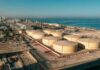 Fragile Ceasefire Teases Cheaper Gas Aerial view of large oil storage tanks near a coastal area