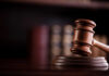 Congressman’s Gambles Rattle DOJ A wooden gavel resting on a sound block with blurred law books in the background