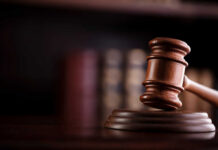 A wooden gavel resting on a sound block with blurred law books in the background
