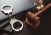 Crime Drop Boast Sparks Doubt Handcuffs and a gavel on a desk with legal books