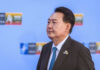 A political leader in formal attire at a conference with a serious expression
