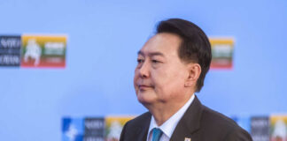 A political leader in formal attire at a conference with a serious expression