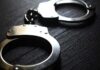 Close-up of metallic handcuffs on a textured surface