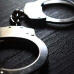 Close-up of metallic handcuffs on a textured surface