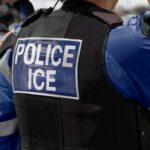 Close-up of a police officer's vest with 'POLICE ICE' label