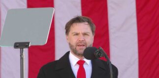 Man speaking at a podium with an American flag backdrop