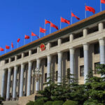 Pentagon Flags Tech Giants As Risks Facade of a government building adorned with red flags and a national emblem