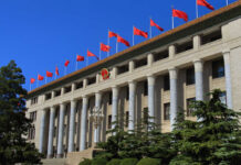 Pentagon Flags Tech Giants As Risks Facade of a government building adorned with red flags and a national emblem